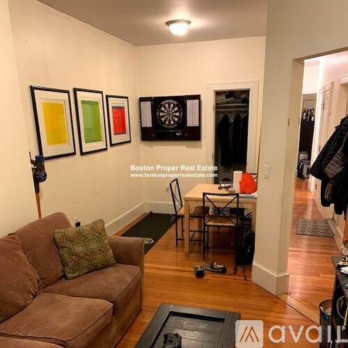 A living room with a brown couch and a dart board on the wall.