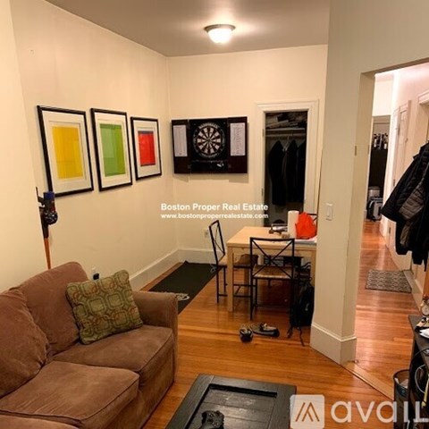 A living room with a brown couch and a dart board on the wall.