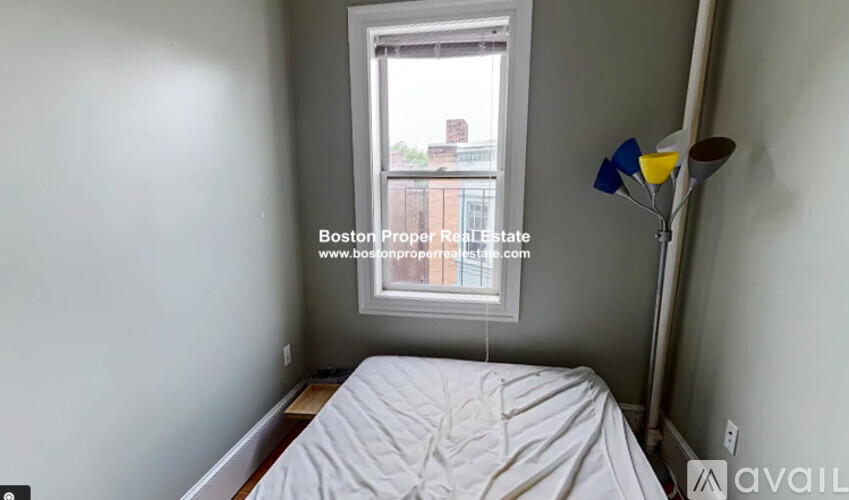 A bedroom with a bed, a window, and a lamp.