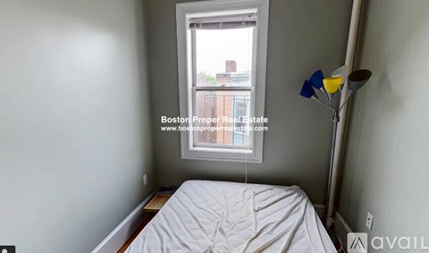 A bedroom with a bed, a window, and a lamp.