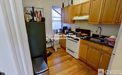 A kitchen with wooden cabinets and a black refrigerator.