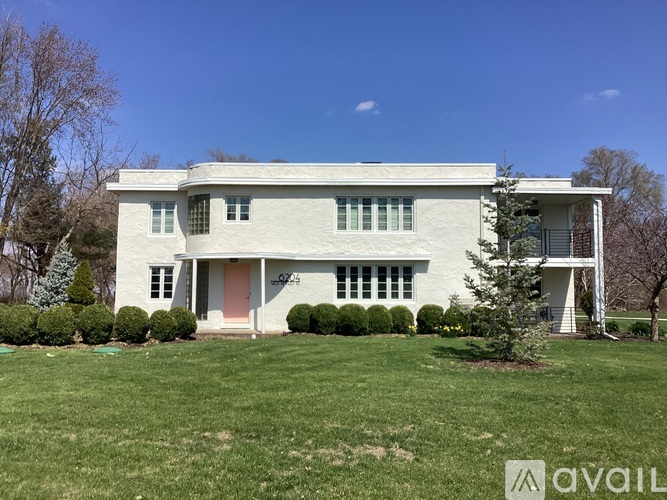 A white house with a red door and windows surrounded by green grass.