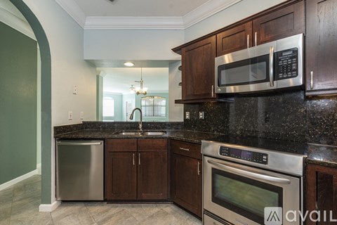 A kitchen with dark wood cabinets and stainless steel appliances.