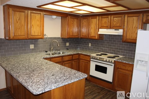 A kitchen with wooden cabinets and a granite countertop.