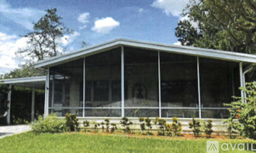 A glass house with trees in the background.