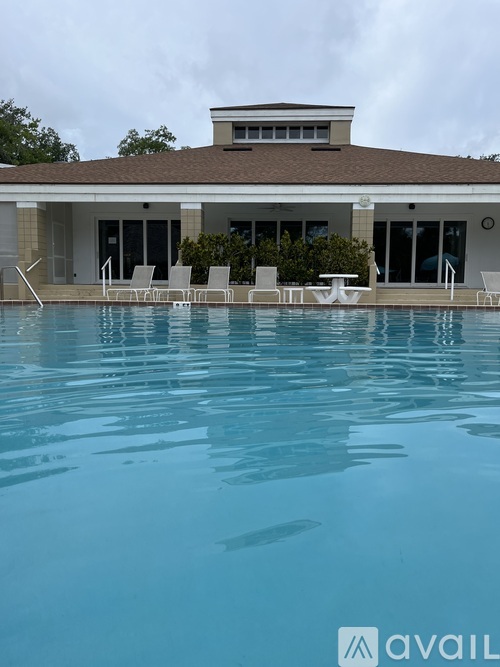 A pool in front of a house with a white fence.