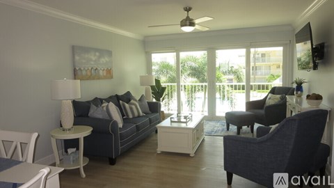 A living room with a grey couch, a white side table, and a ceiling fan.