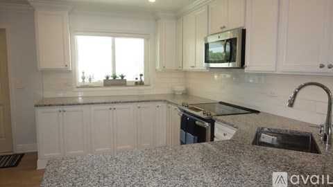 A kitchen with white cabinets and a granite countertop.