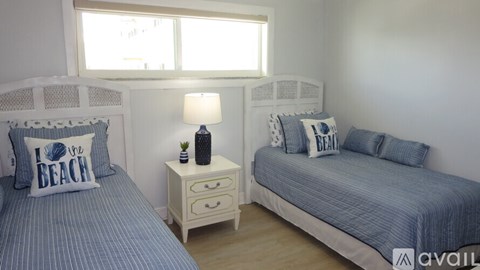 A bedroom with two beds, one with a blue and white striped bedspread and the other with a white bedspread.