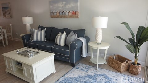 A living room with a blue couch, a white coffee table, and a plant.