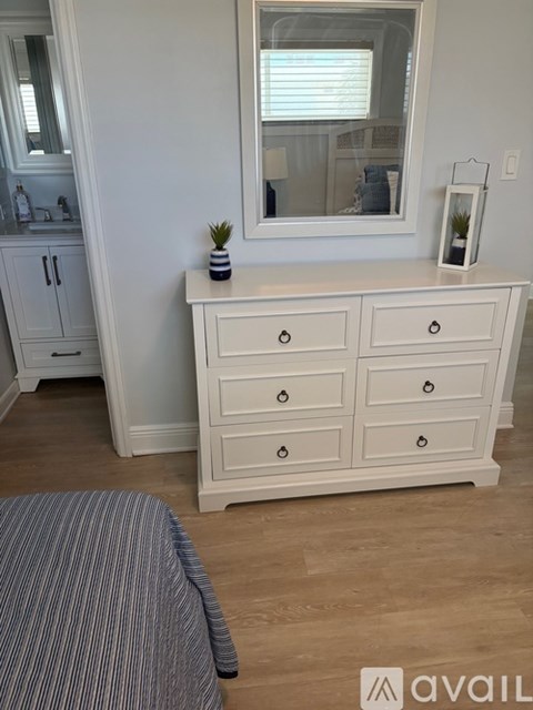A white dresser with a mirror above it and a plant on top.