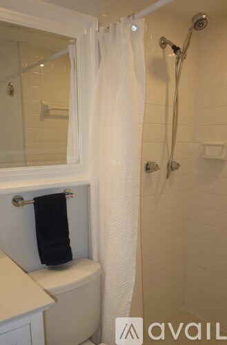 A bathroom with a toilet, a shower curtain, and a towel hanging on the towel rack.