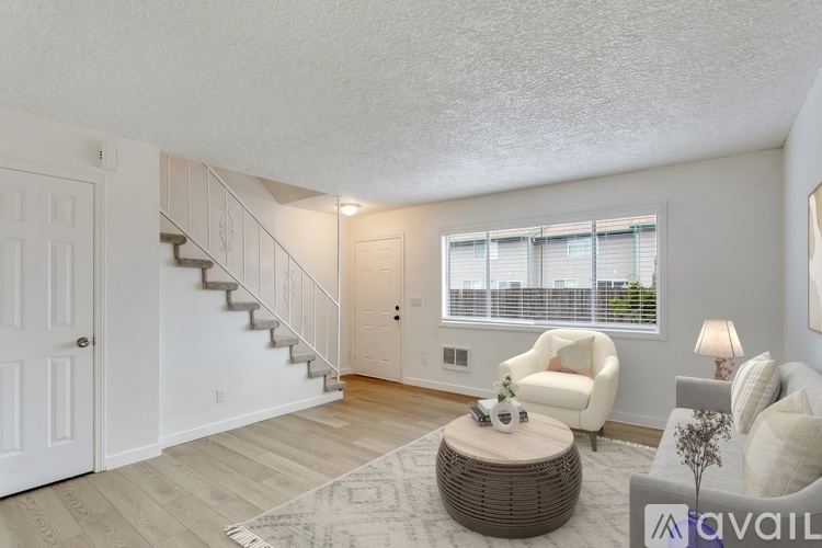 A living room with a staircase and a white chair.