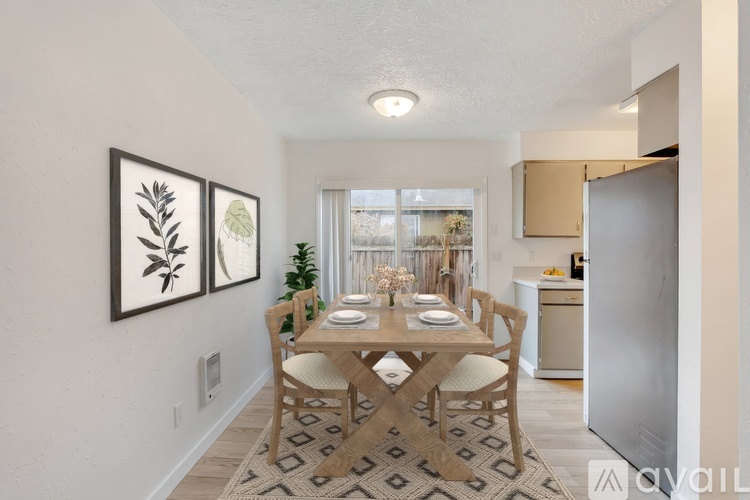 A dining room with a table set for two and a framed picture on the wall.