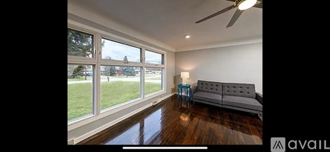 A living room with a grey couch and a ceiling fan.