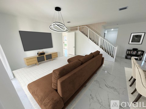 A living room with a brown couch and a television mounted on the wall.