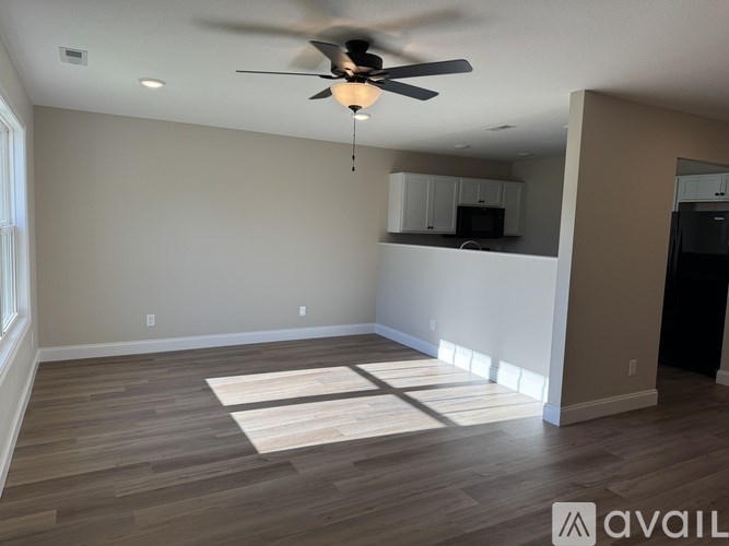 A spacious room with a ceiling fan and wooden flooring.