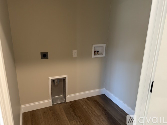 A room with a white door and a small ventilation shaft in the floor.