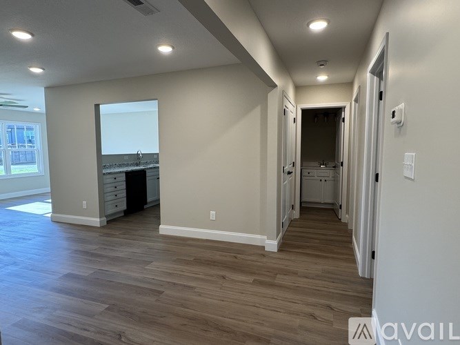 A spacious room with wood flooring and a large window.