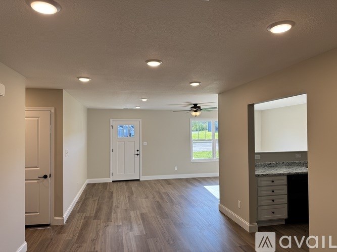 A spacious room with a door, a window, and a ceiling fan.