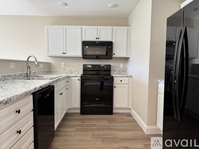 A kitchen with black appliances and white cabinets.