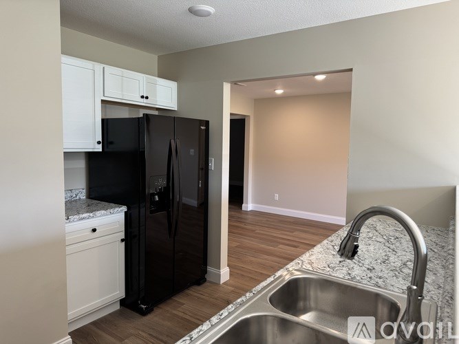 A kitchen with a black refrigerator and a stainless steel sink.