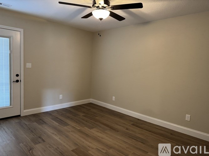 A room with a ceiling fan and wooden flooring.