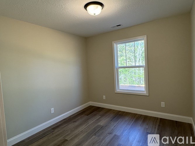 A room with a window and wooden flooring.