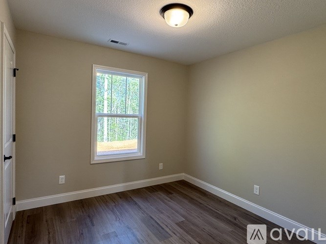 A room with a window and wooden flooring is available for rent.