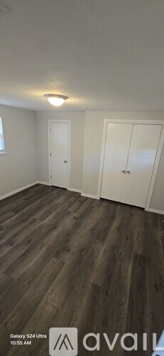 A room with wooden flooring and two white doors.