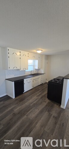 A kitchen with white cabinets and a wooden floor.