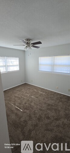 A room with a ceiling fan and carpeted floor.