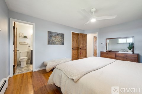 A bedroom with a large bed, a dresser with a mirror, and a painting on the wall.