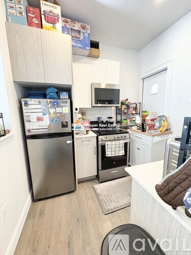 A small kitchen with a refrigerator, oven, microwave, and a dining table.