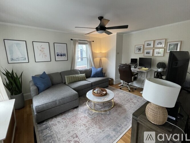 A living room with a grey couch, a coffee table, and a ceiling fan.