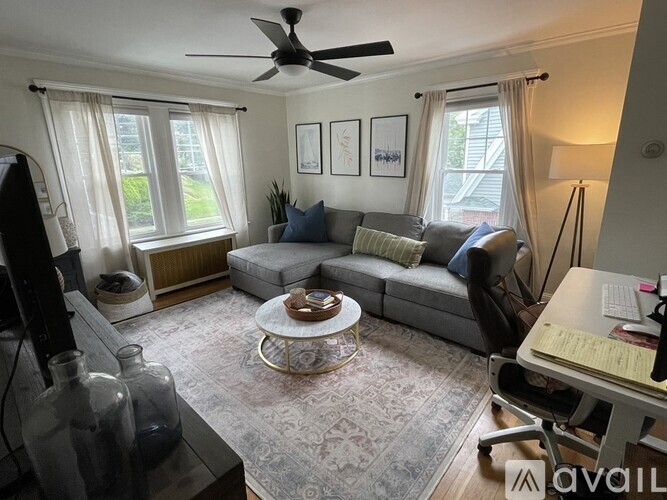 A living room with a grey couch, a coffee table, and a ceiling fan.
