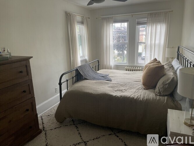 A bedroom with a bed, dresser, and window.