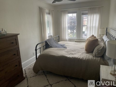 A bedroom with a bed, dresser, and window.