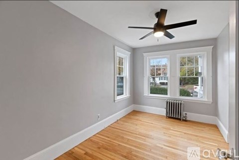 A room with a ceiling fan and a window with a view of a building outside.