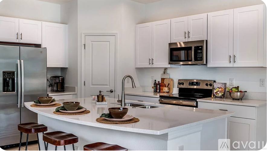 A kitchen with white cabinets and a white island with a sink.