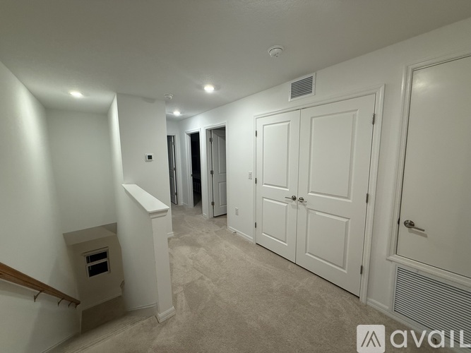 A spacious hallway with white doors and a carpeted floor.