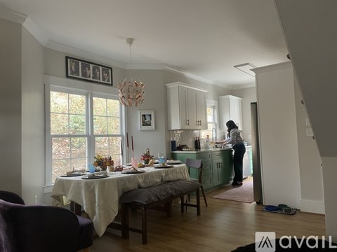 A woman is standing in a kitchen with a table set for a meal.