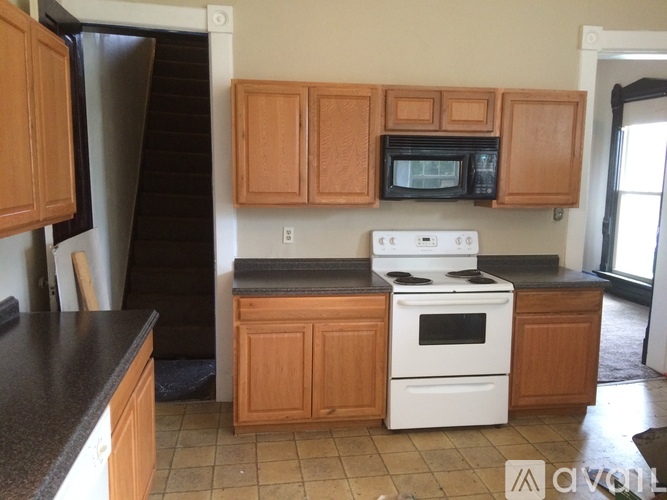 A kitchen with wooden cabinets and a white stove top oven.