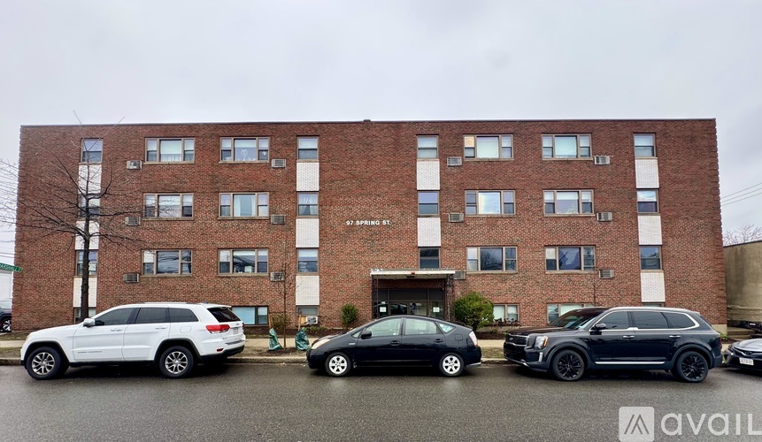 A black car is parked in front of a brick building.