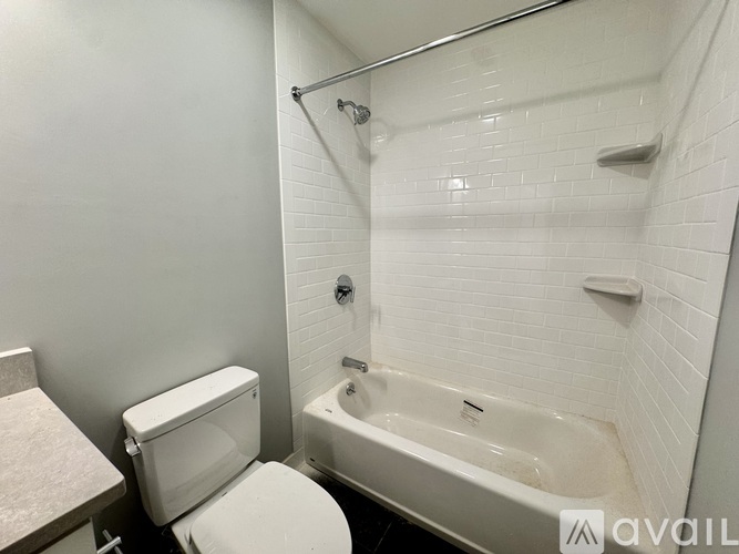 A white toilet and bathtub in a bathroom with white tiles.