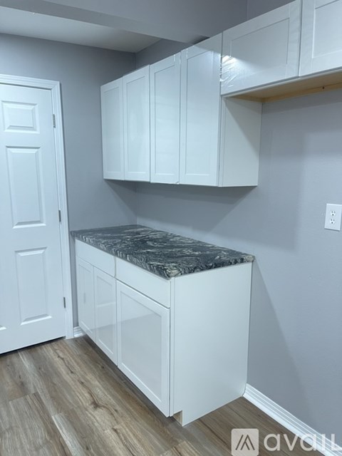 A kitchen with white cabinets and a marble countertop.