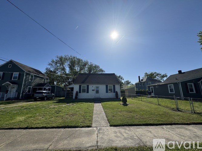 A sunny day in a residential area with houses and a car parked on the street.