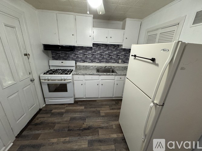 A kitchen with white cabinets and a white fridge.