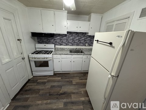 A kitchen with white cabinets and a white fridge.