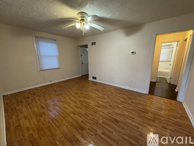 A room with wooden flooring and a ceiling fan.